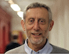 Shows a head shot of Michael Rosen, poet Michael is a mature man with brownish grey hair and a short grey beard he is wearing a sweater over a shirt